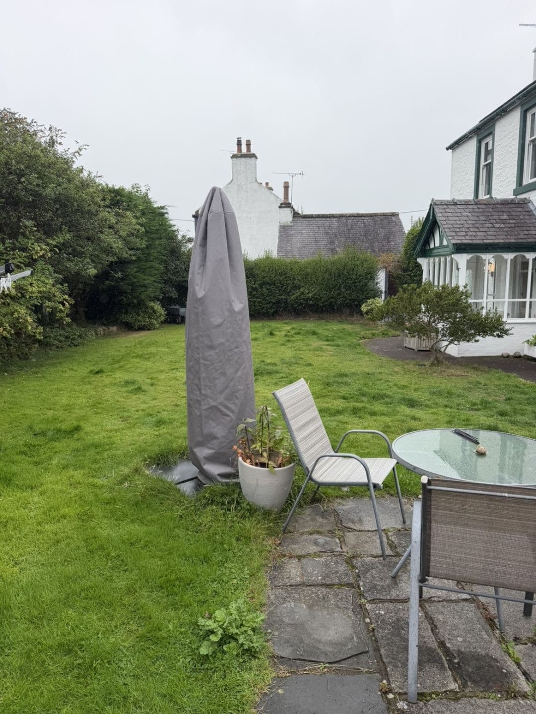 Long grass around the patio furniture before the garden maintenance visit in Lochmaben